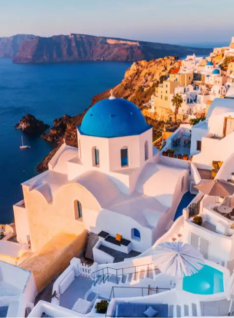 Village d'Oia Santorini avec église à dôme bleu et vue sur caldeira, voyage sur mesure en Grèce
