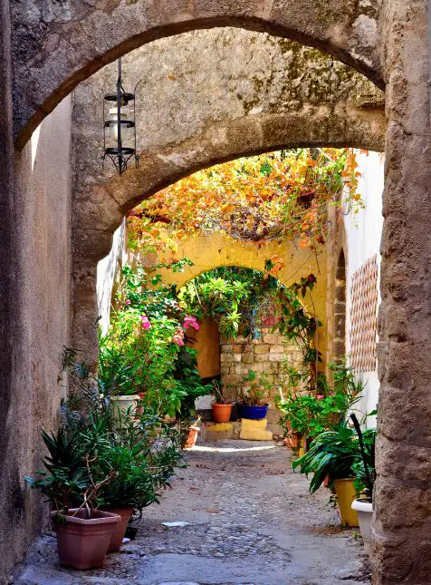 Ruelle voûtée grecque traditionnelle avec arches en pierre et plantes, voyage sur mesure en Grèce