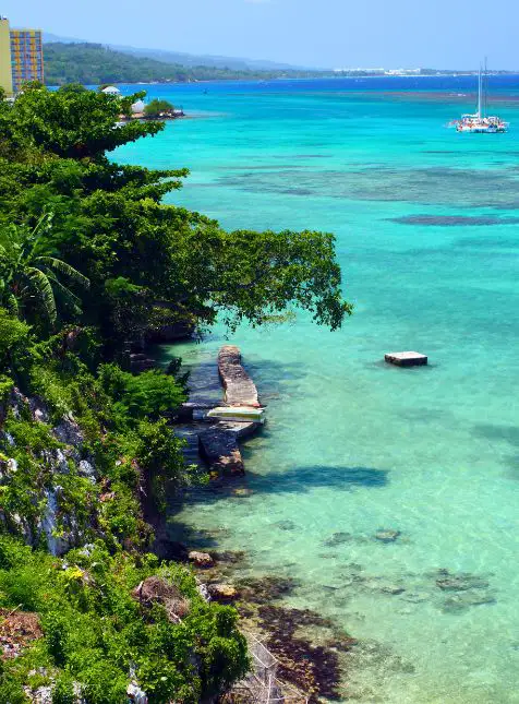 Baie jamaïcaine aux eaux émeraude avec bateaux et végétation tropicale - voyage sur mesure en Jamaïque