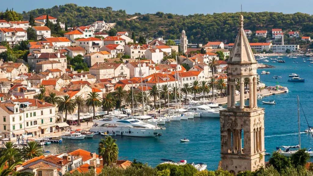 Port de Hvar avec clocher vénitien, palmiers et bateaux de plaisance pour voyage sur mesure en Croatie