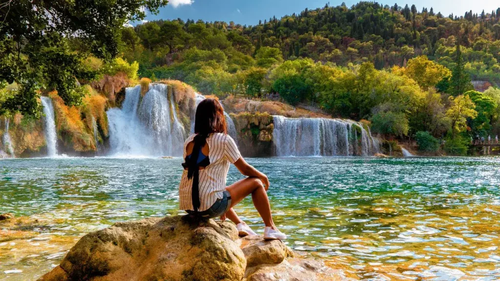 Femme contemplant des cascades naturelles dans un parc national croate pour voyage sur mesure en Croatie