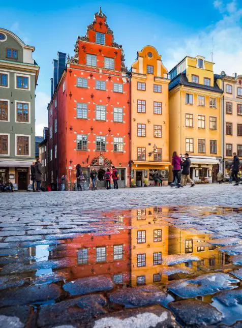 Façades colorées de Gamla Stan Stockholm se reflétant sur pavés mouillés pour voyage sur mesure en Suède authentique