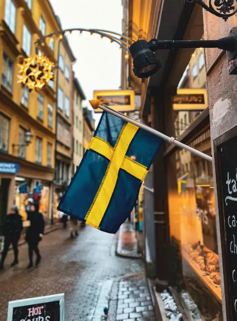 Rue pavée de Stockholm avec drapeau suédois et boutiques pour voyage sur mesure en Suède urbain authentique