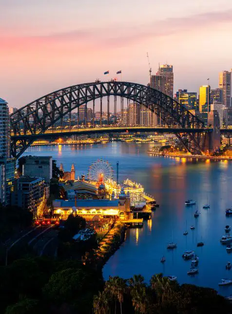 Harbour Bridge de Sydney illuminé au coucher de soleil avec Opera House pour voyage sur mesure en Australie Les Sens du Voyage