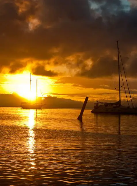 Coucher de soleil dramatique orangé avec voiliers en silhouette sur lagon fidjien pour voyage sur mesure Fidji romantique