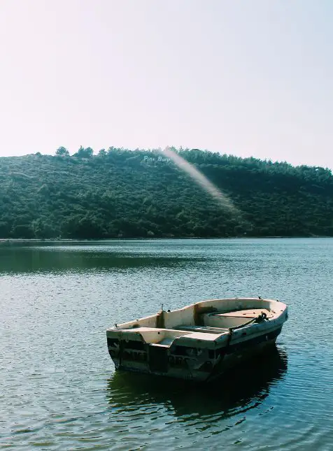 Barque en bois traditionnelle sur lac finlandais calme entouré de forêts pour voyage sur mesure Finlande