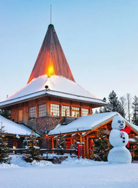 Village du Père Noël enneigé à Rovaniemi en Laponie avec bonhomme de neige et illuminations pour voyage sur mesure Finlande