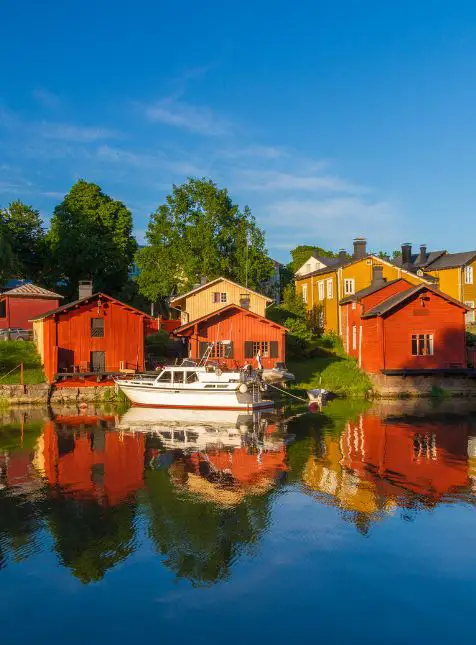 Maisons en bois rouges et jaunes au bord de l'eau à Porvoo avec bateau pour voyage sur mesure Finlande