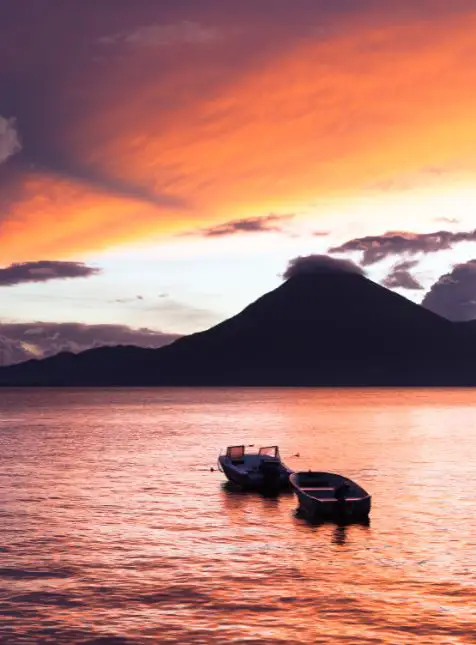 Coucher de soleil rose et orange sur le lac Atitlán avec volcans lors d'un voyage sur mesure Guatemala organisé par Les Sens du Voyage