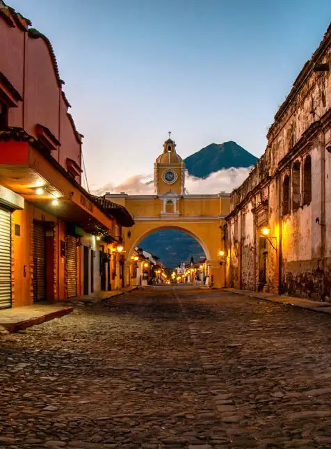 Arche jaune d'Antigua illuminée au coucher du soleil avec volcan Agua pour un voyage sur mesure Guatemala avec Les Sens du Voyage