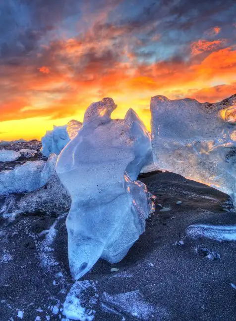 Bloc de glace translucide sur plage de sable noir au coucher de soleil Diamond Beach - voyage sur mesure en Islande avec Les Sens du Voyage