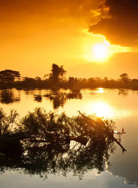 Coucher de soleil doré sur le fleuve Mékong avec reflets orangés lors d'un voyage sur mesure au Laos