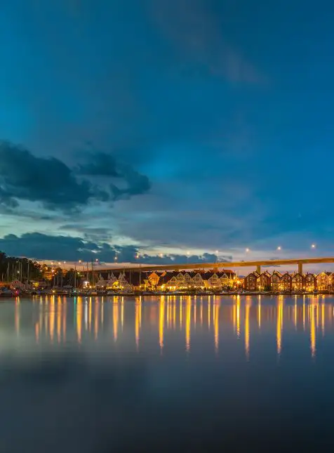 Port norvégien illuminé au crépuscule avec reflets dorés sur l'eau lors d'un voyage sur mesure en Norvège