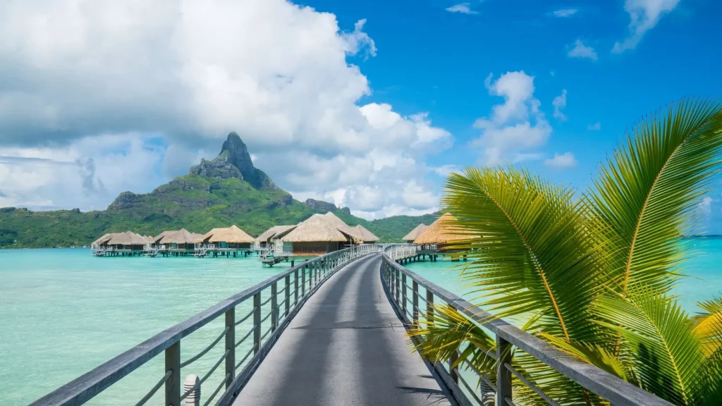 Ponton vers bungalows sur pilotis à Bora Bora avec mont Otemanu - voyage sur mesure en Polynésie - agence Les Sens du Voyage Lyon
