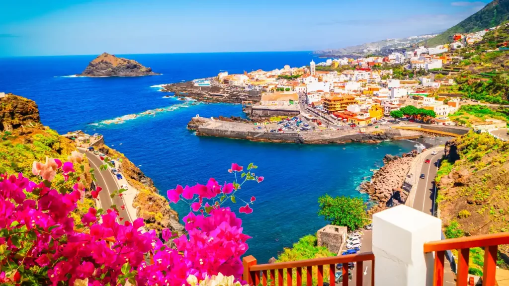 Vue panoramique d’un village côtier aux Canaries avec une baie bleu turquoise et des falaises volcaniques, idéale pour un voyage sur mesure aux Canaries