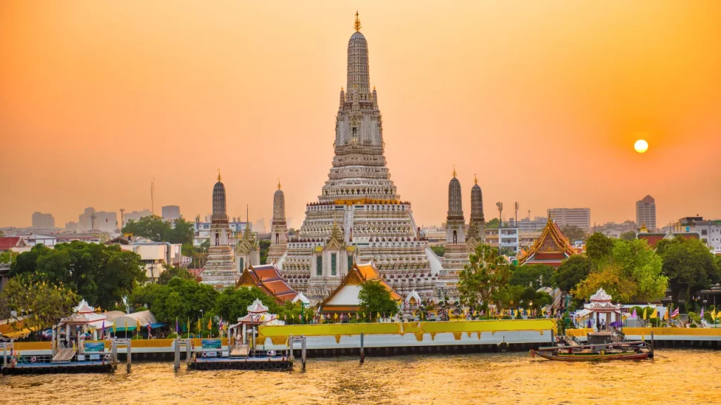 Temple Wat Arun et ses flèches au coucher du soleil sur la rivière Chao Phraya à Bangkok lors d'un voyage sur mesure en Thaïlande