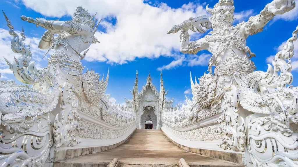 Allée d'entrée du temple blanc Wat Rong Khun à Chiang Rai avec sculptures immaculées lors d'un voyage sur mesure en Thaïlande
