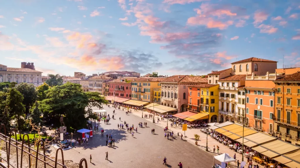 Piazza Bra de Vérone animée avec terrasses de cafés et façades colorées sous un ciel rosé lors d'un voyage sur mesure en Italie