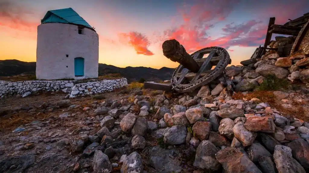 Moulin à vent traditionnel et ancre en bois au coucher du soleil sur l'île de Kimolos lors d'un voyage sur mesure en Grèce