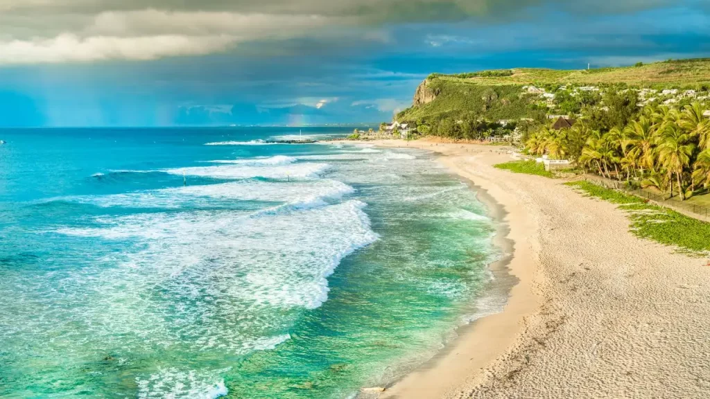 Plage sauvage avec vagues de l'océan Indien, cocotiers et falaise verte lors d'un voyage sur mesure à La Réunion