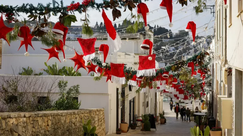 Ruelle d'Alberobello décorée de bonnets de Noël rouges avec trulli en arrière-plan lors d'un voyage sur mesure en Italie
