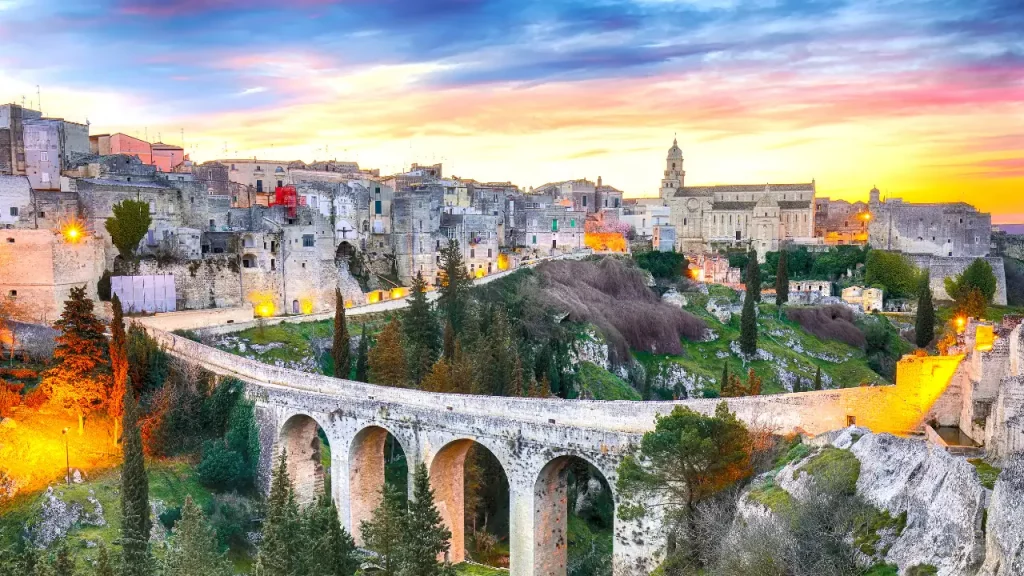 Aqueduc médiéval et vieille ville de Gravina di Puglia illuminés au coucher du soleil lors d'un voyage sur mesure en Italie