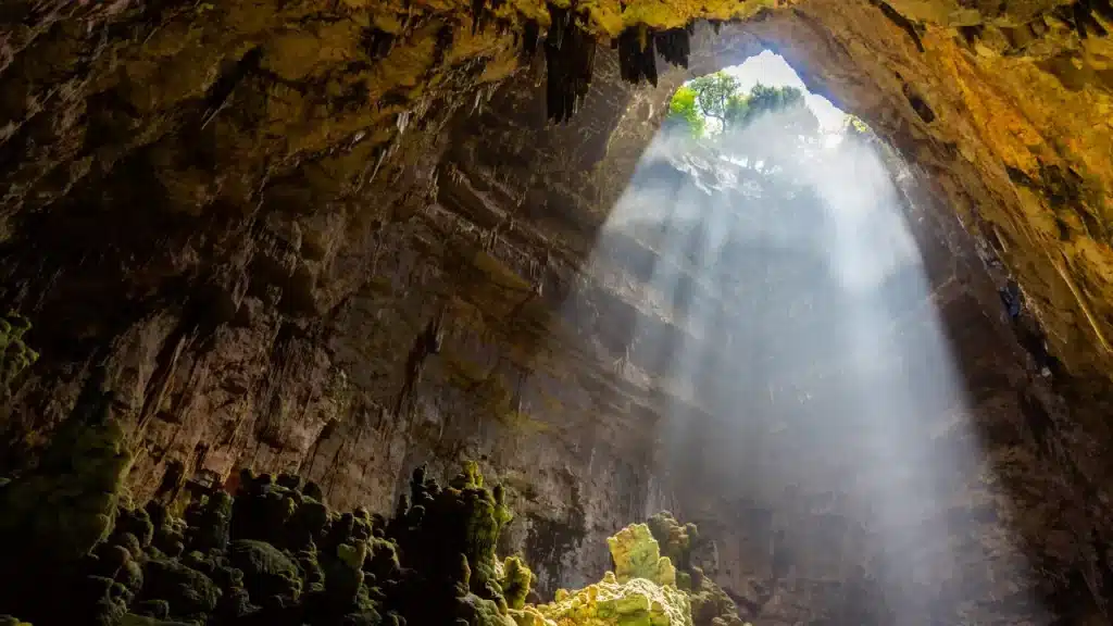 Rayon de lumière naturelle traversant l'ouverture de la grotte de Castellana avec stalactites lors d'un voyage sur mesure en Italie