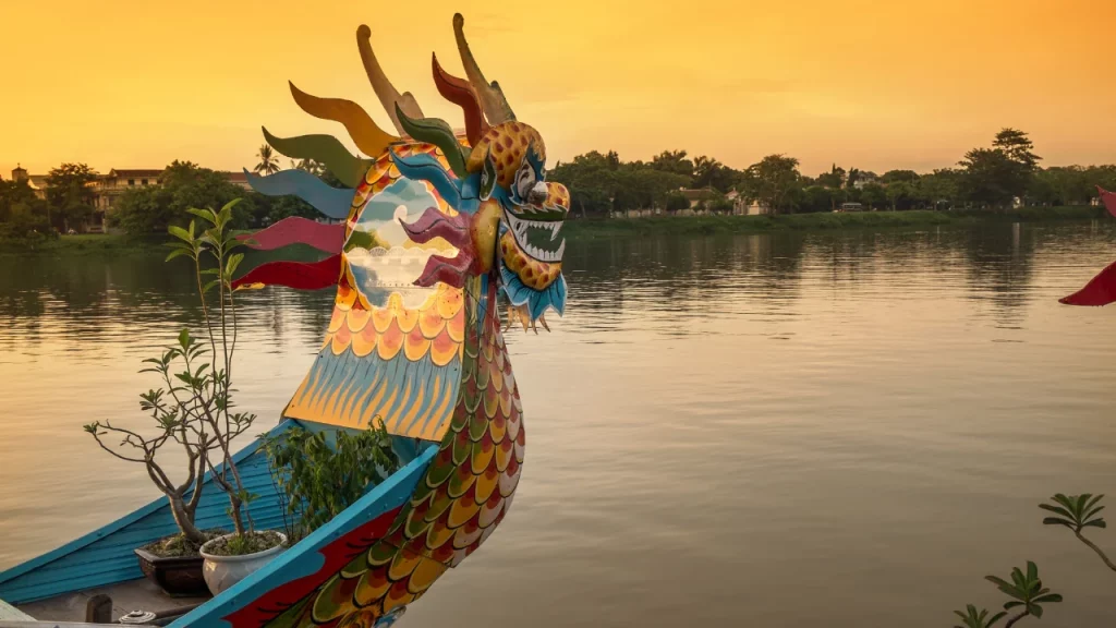 Barque-dragon colorée sur la rivière des Parfums à Hué au coucher du soleil lors d'un voyage sur mesure au Vietnam