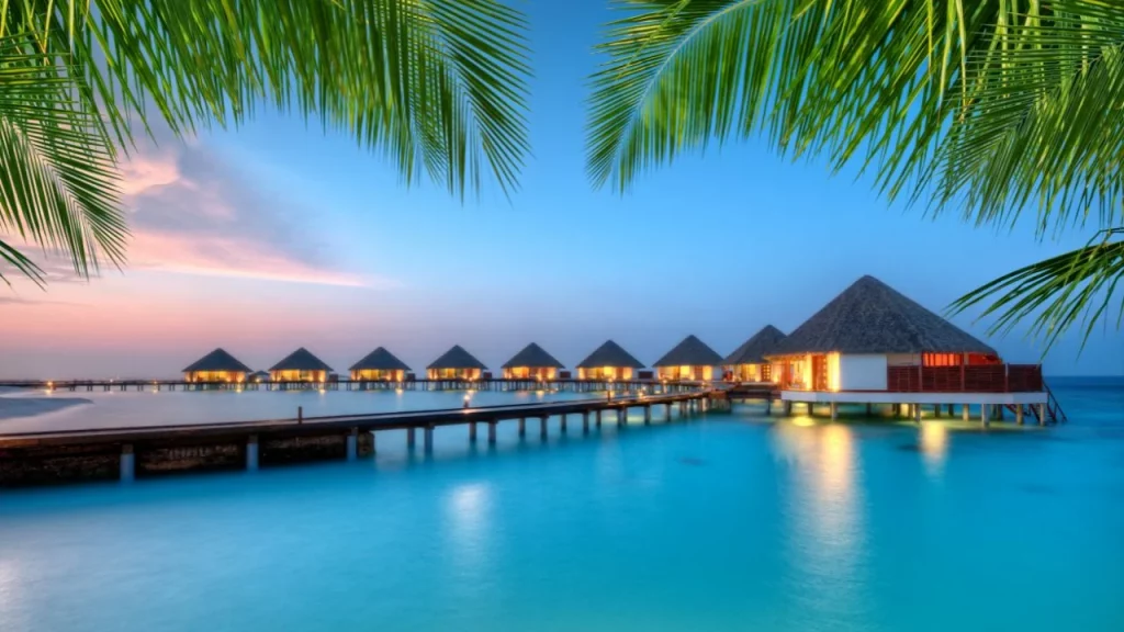 Bungalows sur pilotis illuminés au coucher du soleil sur un lagon turquoise lors d'un voyage de noces sur mesure aux Maldives