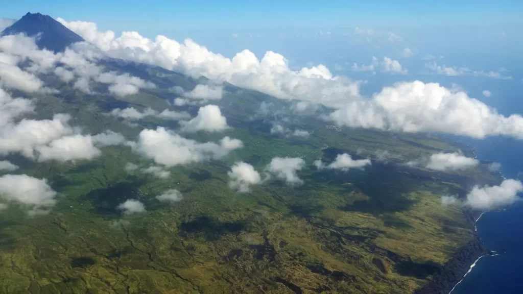 Vue aérienne d'une île volcanique verdoyante entourée de nuages