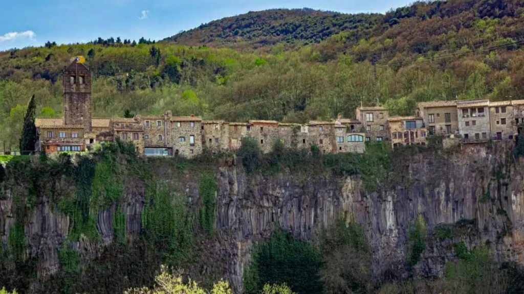 Village médiéval perché sur falaise basaltique entouré de forêts