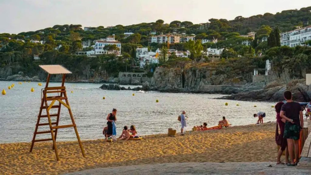 Plage méditerranéenne animée avec tour de surveillance et village côtier